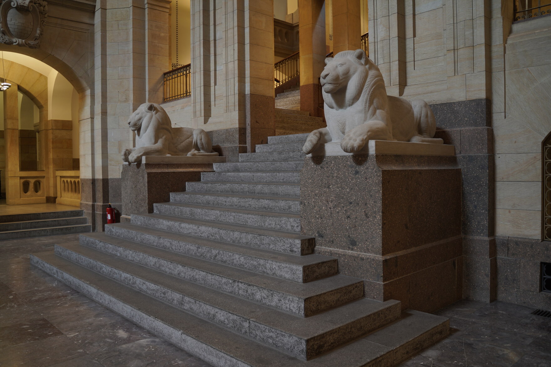 Zwei steinerne Löwen sitzen neben einer Treppe.